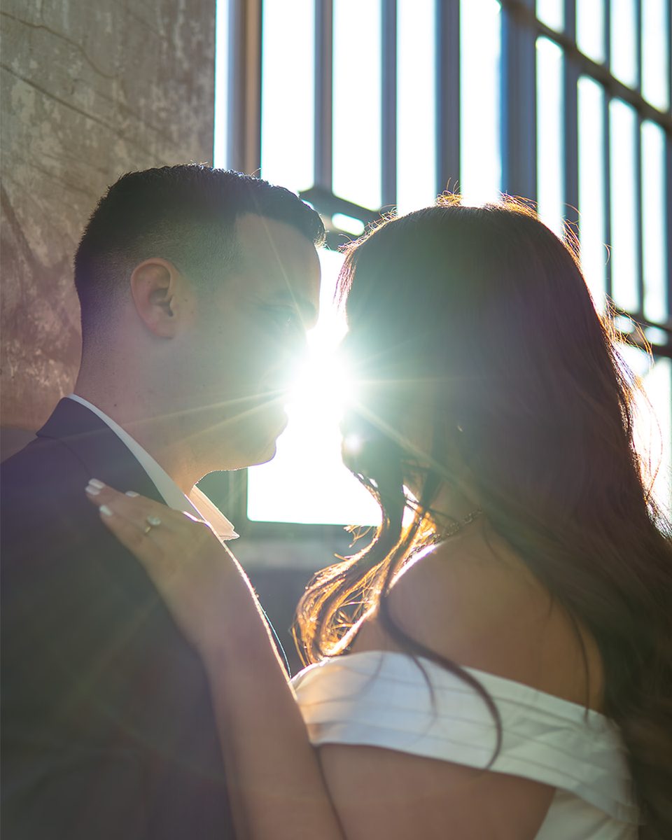 Engaged couple backlit by sun flare at Crosstown Concourse, Memphis