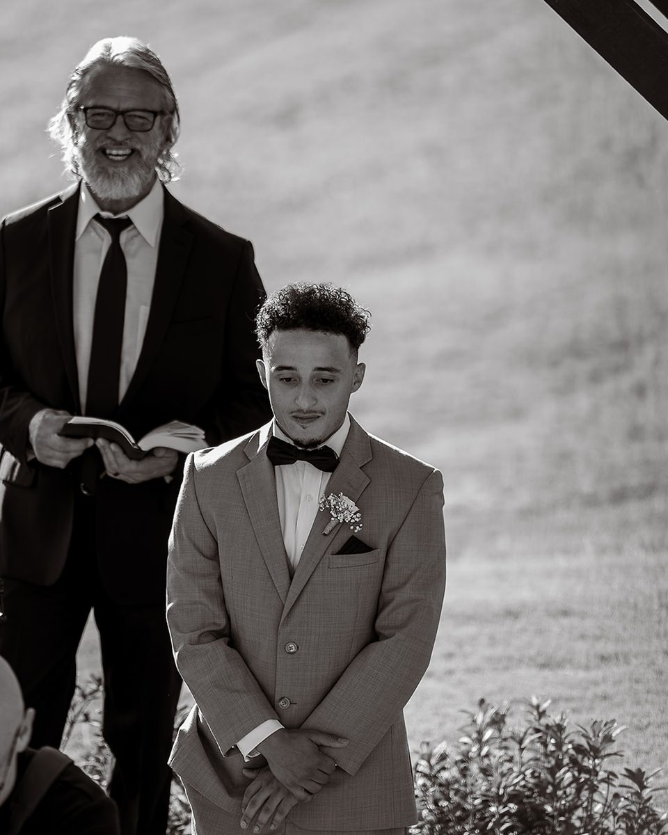 Groom listening to the officiant at a Robinshaw elopement, black and white
